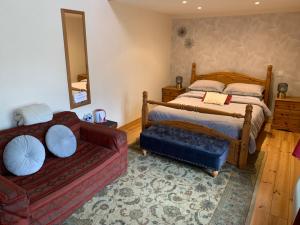 1 dormitorio con cama, sofá y espejo en Chez Helen en Marsac