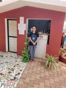 a man standing in the doorway of a red building at LEON HOME STAY in Bogmolo