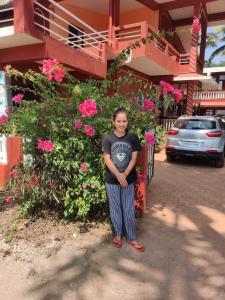 a woman standing in front of a building with flowers at LEON HOME STAY in Bogmolo