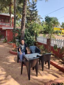 een man in een stoel naast een tafel bij LEON HOME STAY in Bogmalo