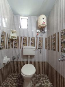 een badkamer met een toilet en een lampje aan de muur bij LEON HOME STAY in Bogmalo