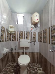 a bathroom with a toilet and a light on the wall at LEON HOME STAY in Bogmalo