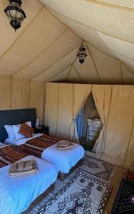 a bedroom with two beds in a tent at Erg Chebbi Luxury Camp in Merzouga