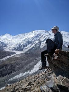 un hombre sentado en una roca mirando una montaña en Alay Travel house, en Sary-Mogul