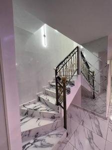 spiralne schody z marmurowymi podłogami i klatką schodową w obiekcie aPogee Home w mieście Abudża