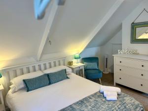 a bedroom with a white bed and a blue chair at Fowey River Views in Fowey