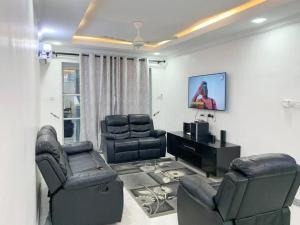 - un salon avec deux chaises et une télévision à écran plat dans l'établissement BUDGET HOMES ZANZIBAR, à Ngambo
