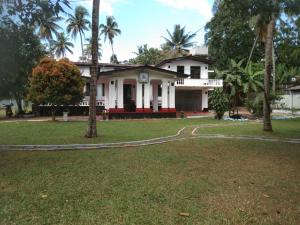 a white house with palm trees in front of it at Leisure Home Human Care Center in Gonawala