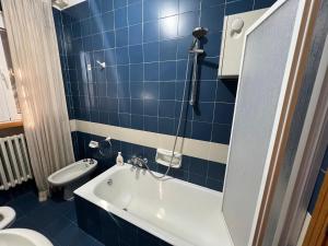 baño de azulejos azules con bañera y aseo en Casa Mattioli, en Mombaroccio