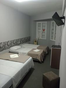 a room with three beds and a flat screen tv at Hotel Rest in Porto Alegre