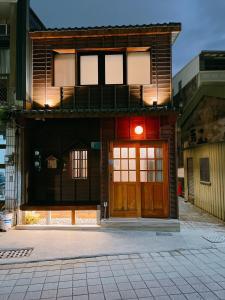 - un bâtiment avec une porte en bois éclairée dans l'établissement 末廣通二館 日式包棟民宿Suehirodori Japanese Entire Homes No2, à Tainan