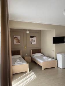 a room with two beds and a flat screen tv at Durmishi Rooms & Apartments & Beach in Sarandë