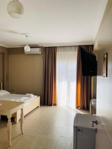Cette chambre comprend un lit, une table et une télévision. dans l'établissement Durmishi Rooms & Apartments & Beach, à Saranda