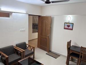 a living room with two chairs and a wooden door at Airport Freshups Cochin in Nedumbassery