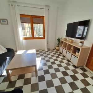 ein Wohnzimmer mit einem TV und einem karierten Boden in der Unterkunft Casa Cervantes in Granada