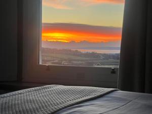 een slaapkamer met uitzicht op de zonsondergang vanuit een raam bij Uplands Inn Cartmel in Cartmel