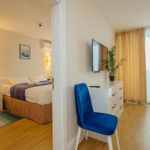 a bedroom with a bed and a blue chair at ORBI CITY -aparthotel in batumi in Batumi