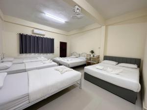 - 3 lits dans une chambre aux murs blancs dans l'établissement Thong Sai Homstay BETONG -ทองใสโฮมสเตย์-, à Betong