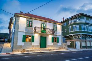 a building with green doors and a balcony on a street at A de Lucía in Muxia