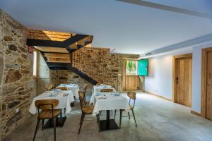 a dining room with tables and chairs and a stone wall at A de Lucía in Muxia