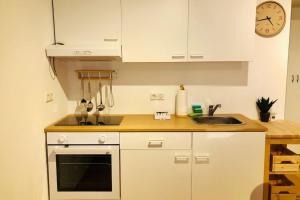 kuchnia z białymi szafkami, zlewem i zegarem w obiekcie Modernes Apartment in Waldstetten w mieście Waldstetten