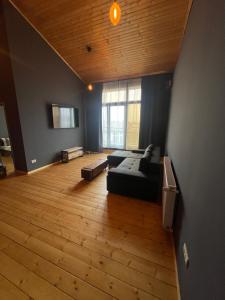salon z czarną kanapą i drewnianą podłogą w obiekcie Residence Otopeni Shr I w mieście Otopeni