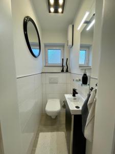 a white bathroom with a toilet and a mirror at Strandliebe Glücksburg in Ulstrupfeld