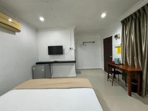 Schlafzimmer mit einem Bett, einem Schreibtisch und einem TV in der Unterkunft Lan Village in Mersing