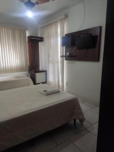 a bedroom with a bed and a tv on the wall at Solar Hotel in São Fidélis