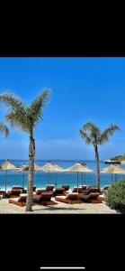 薩蘭達的住宿－Durmishi Rooms & Apartments & Beach，海滩上的一组躺椅和遮阳伞