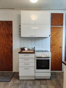uma cozinha com armários brancos e um fogão em Vintage Retreat em Lahti