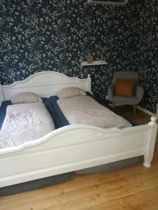 a bedroom with a white bed and a chair at Sinnerskog - Urlaub im alten Bahnhof in Högsby