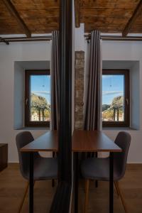 2 Tische und Stühle in einem Zimmer mit Fenstern in der Unterkunft Πέτρινη Αγροικία 2 Stone Manor 2 in Kastraki