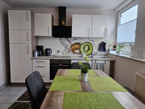 une cuisine avec une table en bois et des chaises ainsi qu'une cuisine avec des placards blancs dans l'établissement Wunderschöne Wohnung mit großen Terrasse in Mülheim Heißen, à Mülheim