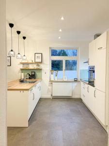 a large kitchen with white cabinets and a window at Ferienwohnung Sauke in Uelzen