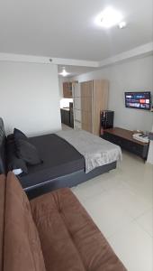 um quarto com uma cama, um sofá e uma televisão em Mataram City Apartment Yogyakarta by ALUN em Kejayan