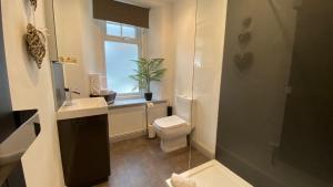 a bathroom with a toilet and a sink and a window at Uplands Inn Cartmel in Cartmel
