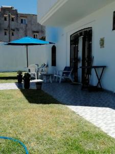 Villa Vue sur Mer في طبرقة: فناء فيه مظلة زرقاء وطاولة وكراسي