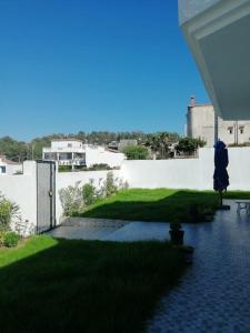 a patio with a green lawn and a white wall at Villa Vue sur Mer in Tabarka