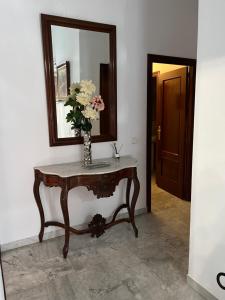 una mesa con un espejo y un jarrón con flores. en Pino Grande 16, en El Viso del Alcor