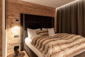 a bedroom with a large bed with a wooden wall at Hollywood Dream Penthouse with private Sauna close Ischgl in Kappl