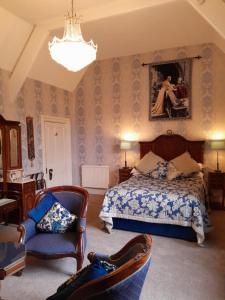 um quarto com uma cama e cadeiras e um lustre em St David's Guesthouse em Haverfordwest