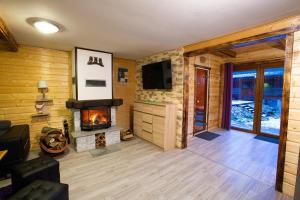 a living room with a fireplace and a television at Domek całoroczny SÓWKA na Kaszubach z banią i sauną na wyłączność, wspólny basen i bilard z domkiem Jeleniówka - Ostrowite Leśna Dolina in Sulęczyno