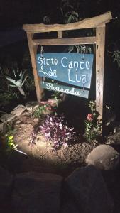 un cartello in mezzo a un giardino con fiori di Pousada Canto da Lua - charme e vista incrível a Carrancas