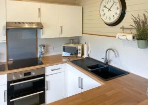 a kitchen with a sink and a clock on the wall at Ivyleaf Combe Lodges in Stratton