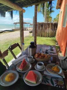 a table with plates of food on it with the beach at Pousada Flor de Elisa frente a praia in Caraíva