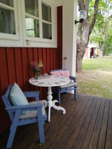 eine Terrasse mit einem Tisch und 2 Stühlen auf einer Veranda in der Unterkunft Sinnerskog - Urlaub im alten Bahnhof in Högsby