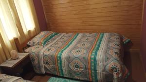 Una cama con edredón en un dormitorio en Cabaña Loremar canaan, en Chonchi