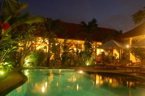 a swimming pool in front of a building at night at Gunakaya Homestay in Sanur