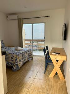 a bedroom with a bed and a table and a window at Hospedaria Cumbuco - Kitnets Completas in Caucaia